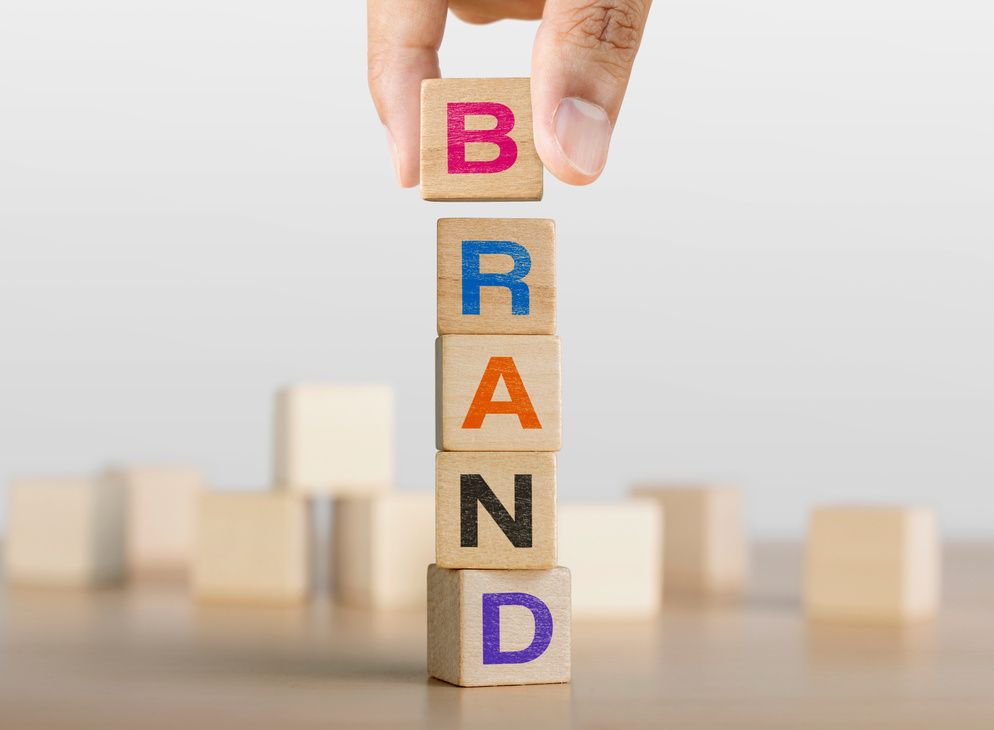 Hand arranging wooden blocks with the word BRAND. Brand building concept.